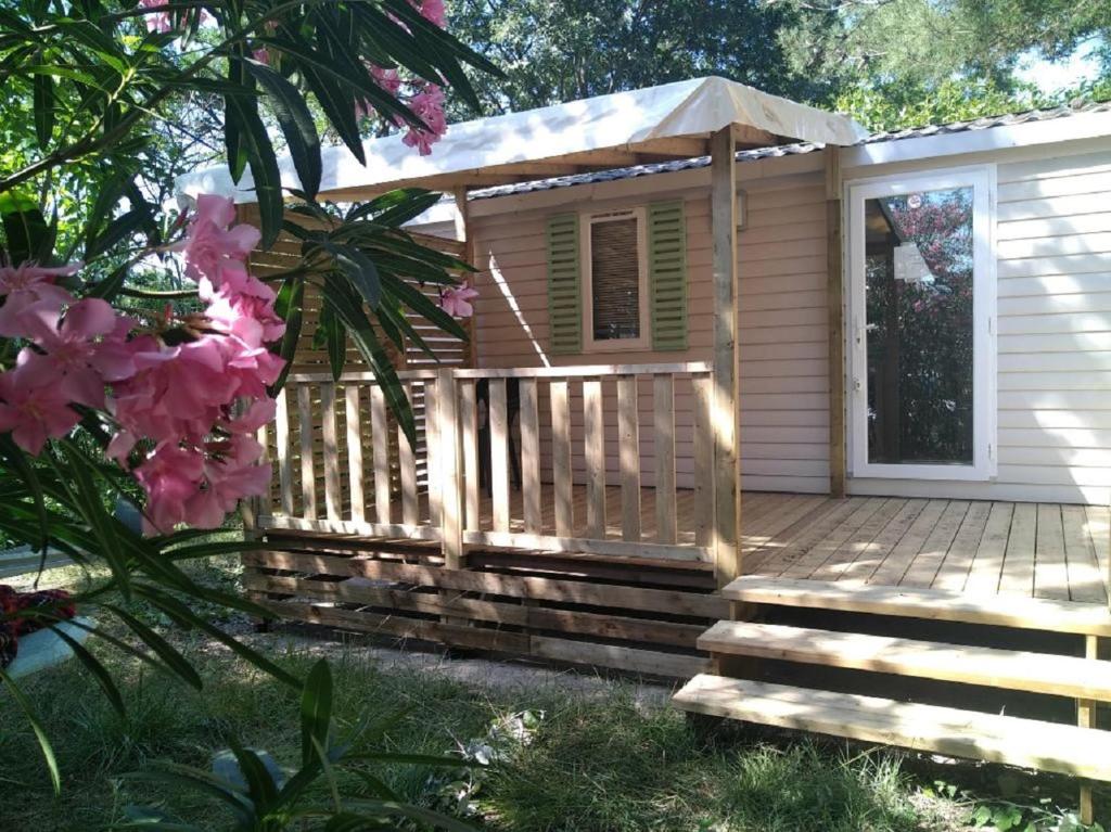 une cabine avec une terrasse et un parasol dans l'établissement Mobilhome 228 proche du Lac , Tv , clim ect Camping, à La Roque-dʼAnthéron