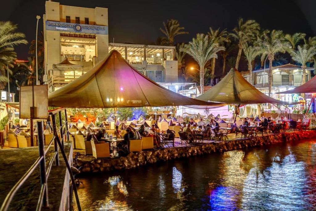 a group of people sitting at tables by a river at night at Al-Amer Chalets in Aqaba