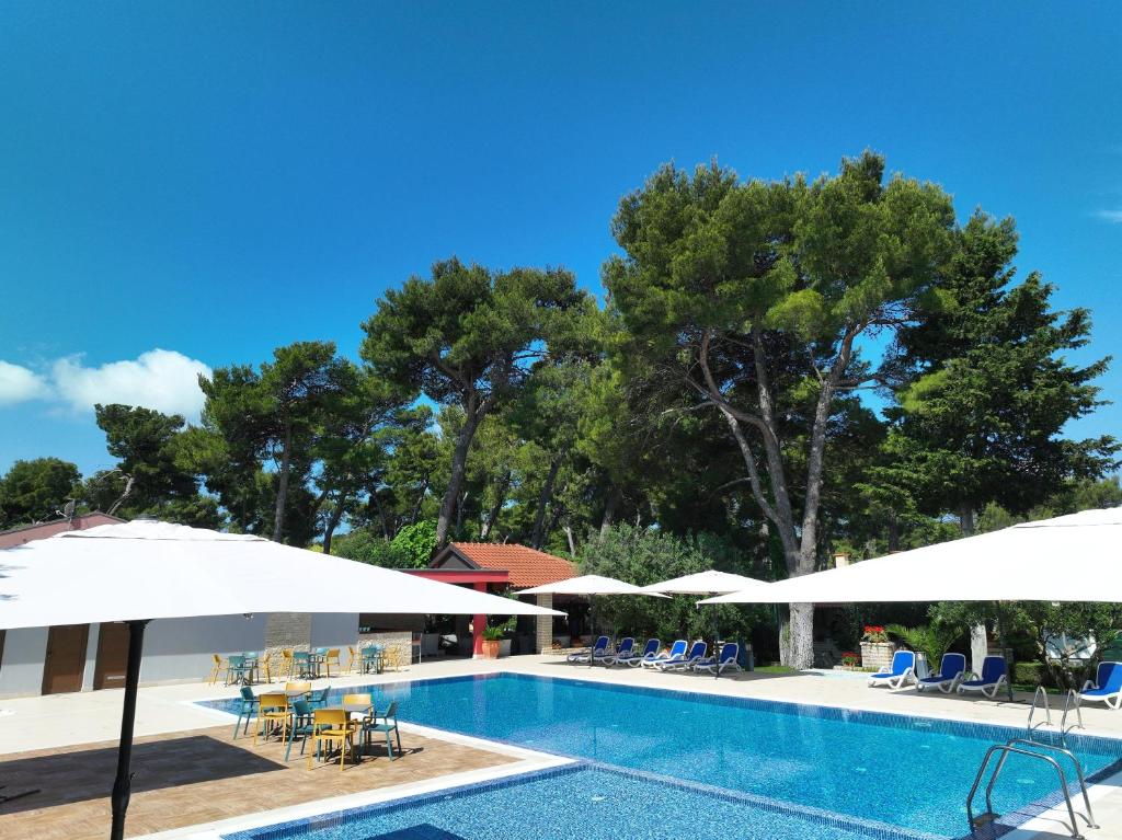 uma piscina com guarda-sóis, mesas e cadeiras em Mediterranean Village San Antonio em Biograd na Moru