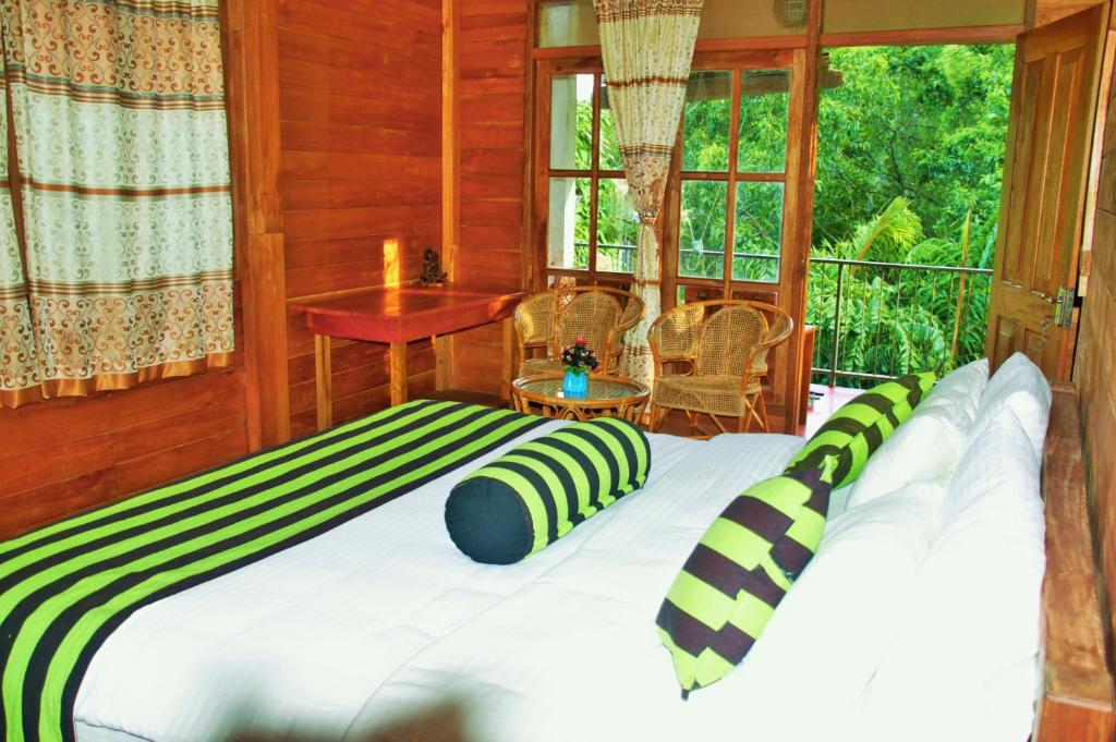 um quarto com uma cama com almofadas verdes e brancas em Green cottage Ella em Ella