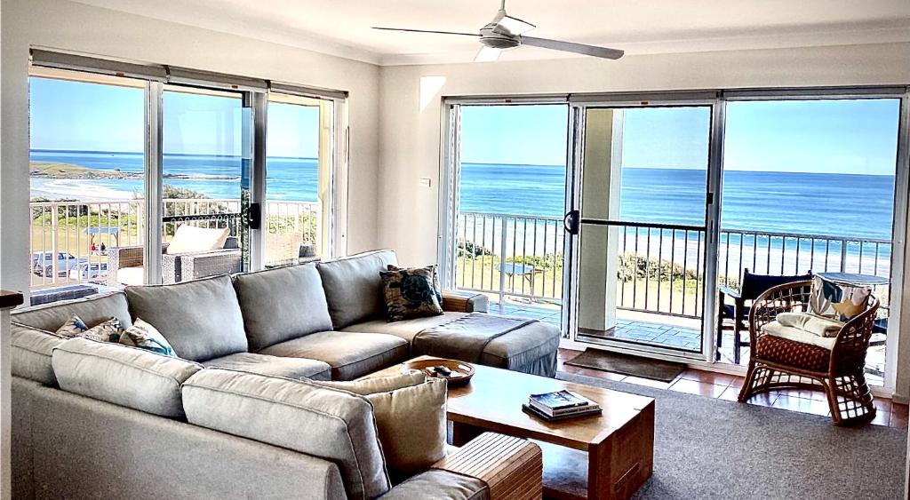 a living room with a couch and a view of the ocean at Pippi Beach Penthouse in Yamba