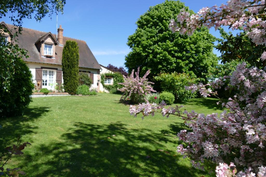 una casa con un patio con árboles y flores en Le Clos des Perraudières, en Cour-Cheverny