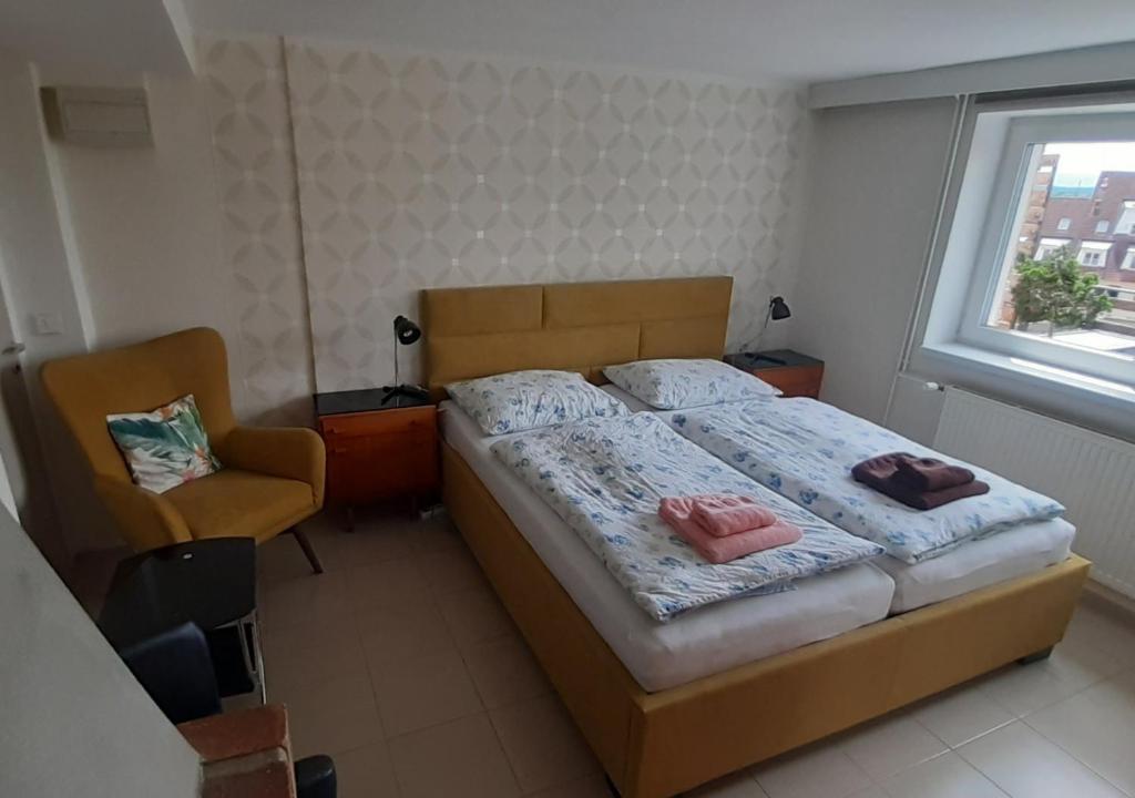 1 dormitorio con 1 cama, 1 silla y 1 ventana en Apartment Adéla en Hluboká nad Vltavou