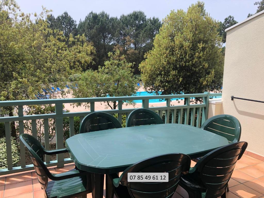 d'une table et de chaises sur un balcon avec piscine. dans l'établissement Bel appartement lumineux à Vieux Boucau avec piscine chauffée - Résidence Domaine du Golf de Pinsolle, à Soustons
