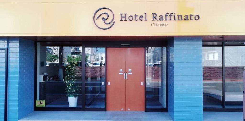 un hotel con una puerta roja frente a un edificio en Hotel Raffinato Chitose en Chitose