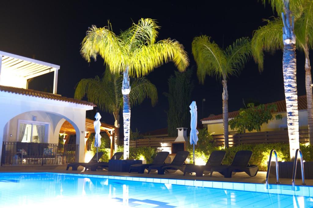einen Pool mit Stühlen und Palmen in der Nacht in der Unterkunft Sunset Villa private complex heated pool in Ayia Napa