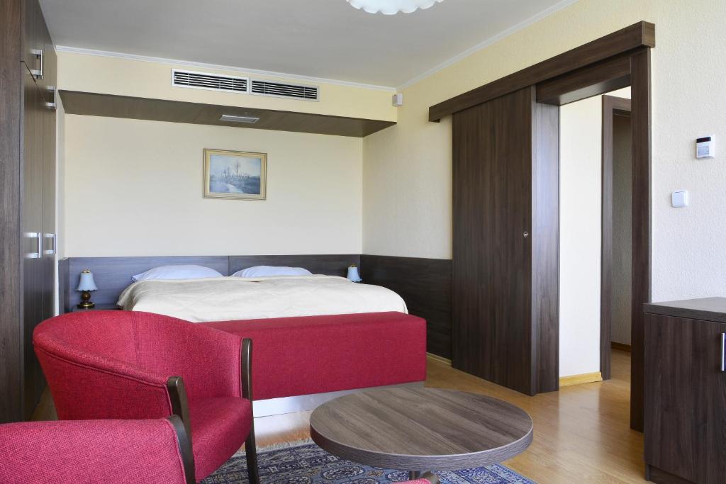 a bedroom with a bed and a red chair at Hotel Olympik in Prague