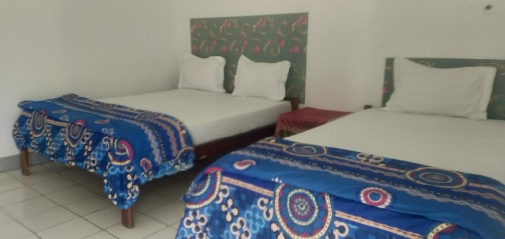 クリムトゥにあるHidayah homestayのベッド2台とベッドスカートが備わる客室です。