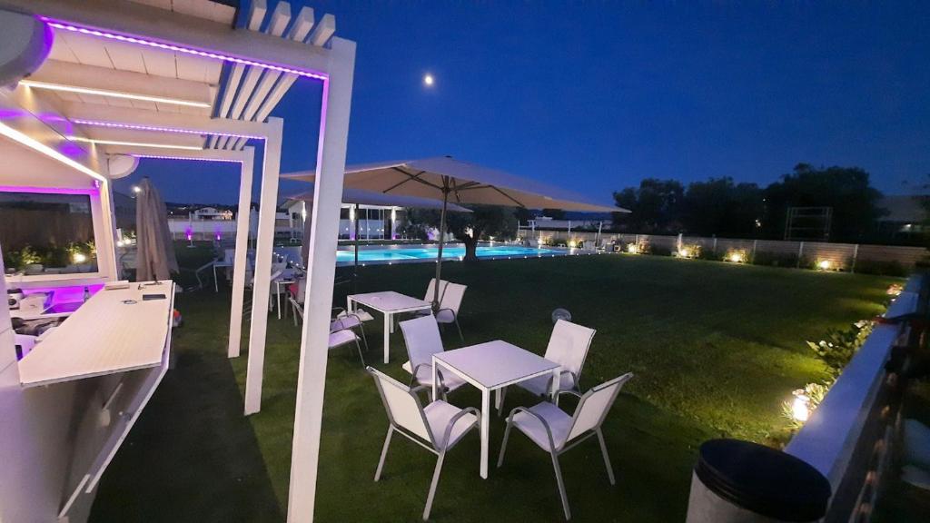 patio ze stołami i krzesłami oraz basen w nocy w obiekcie Luxury Pool Suites - Città Bianca w mieście Pescara