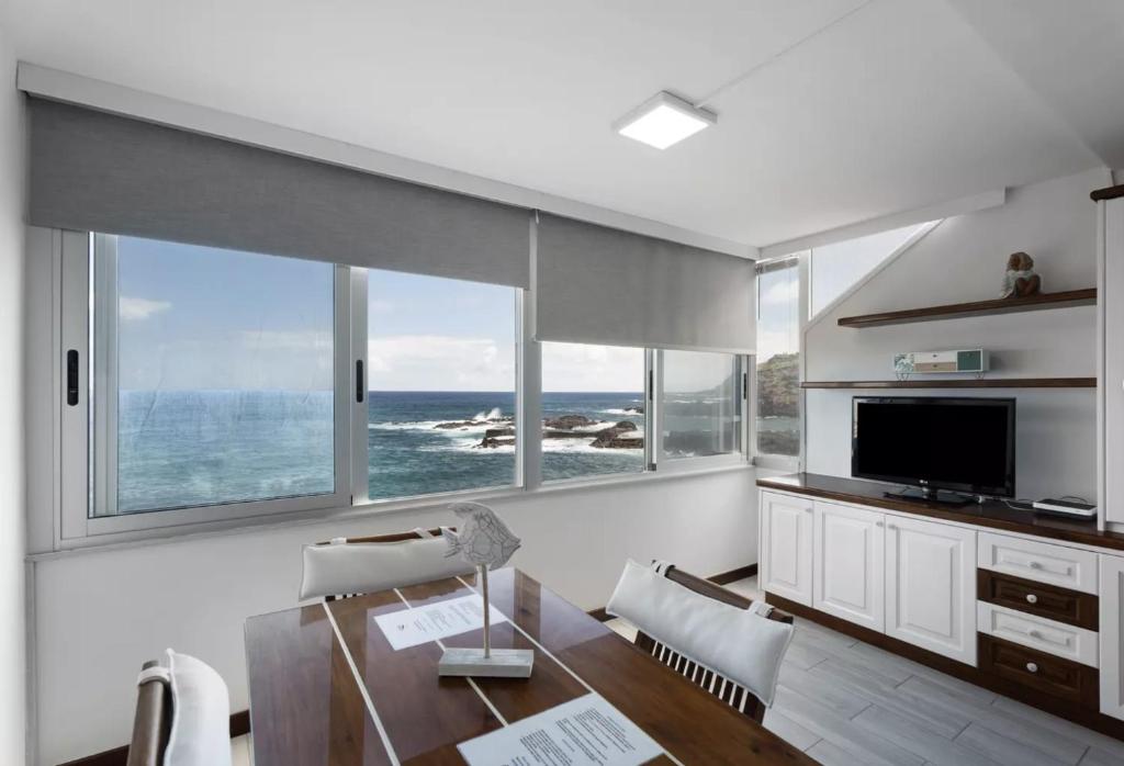 - un salon avec une table et quelques fenêtres dans l'établissement Roque Mar Apartamento Atardecer, à Santa Cruz de Tenerife