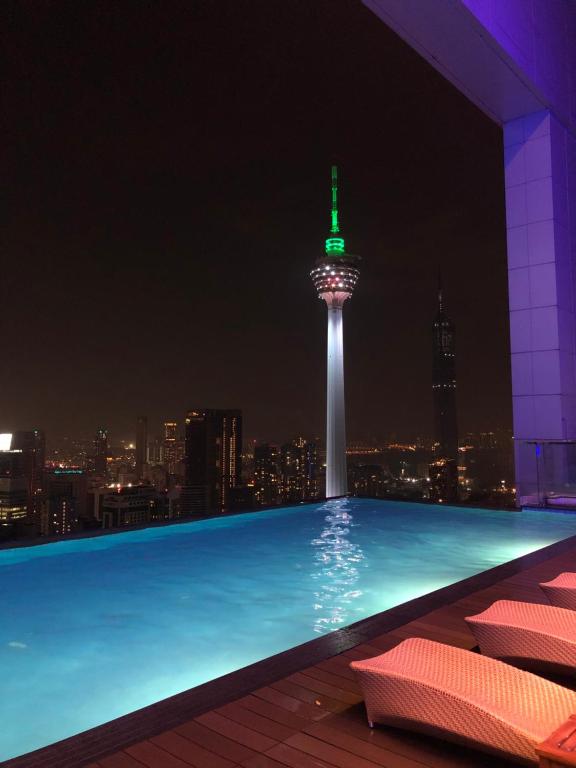 a swimming pool with a view of the space needle at night at Pool View Platinum KLCC in Kuala Lumpur