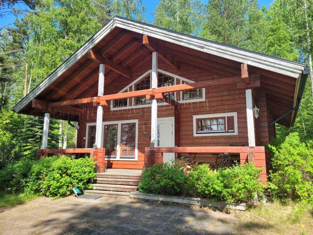 a log cabin with a porch and stairs to the front of it at Villa Okra in Rastinniemi