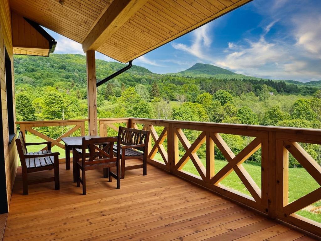 a porch with a table and chairs and a view of the mountains at Bukowe Tarasy in Wetlina