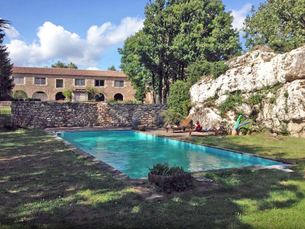 una piscina en un patio junto a una pared de piedra en Mas des Clauzals, en Le Cros