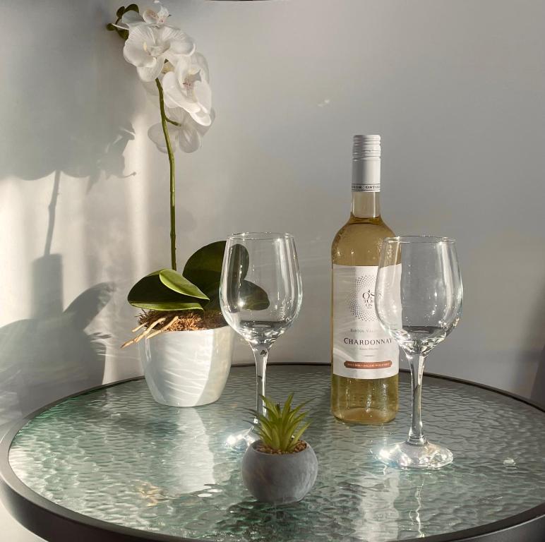 a bottle of wine and two wine glasses on a table at Lux apartments in Orosháza