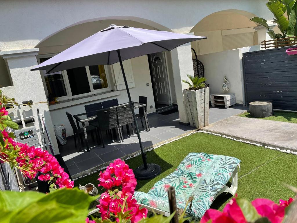 un patio avec un parasol, une table et des chaises dans l'établissement Mini villa à 200m de la plage, à Borgo