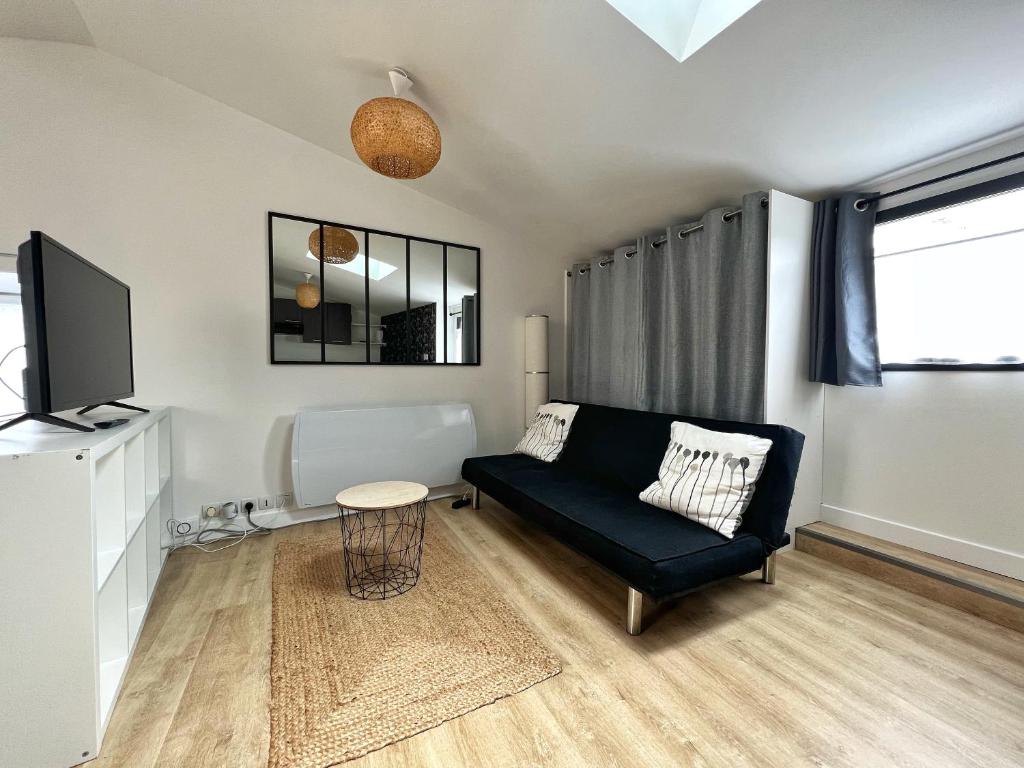 sala de estar con sofá negro y TV en Le Petit Cosy - terrasse privée, en Lagord