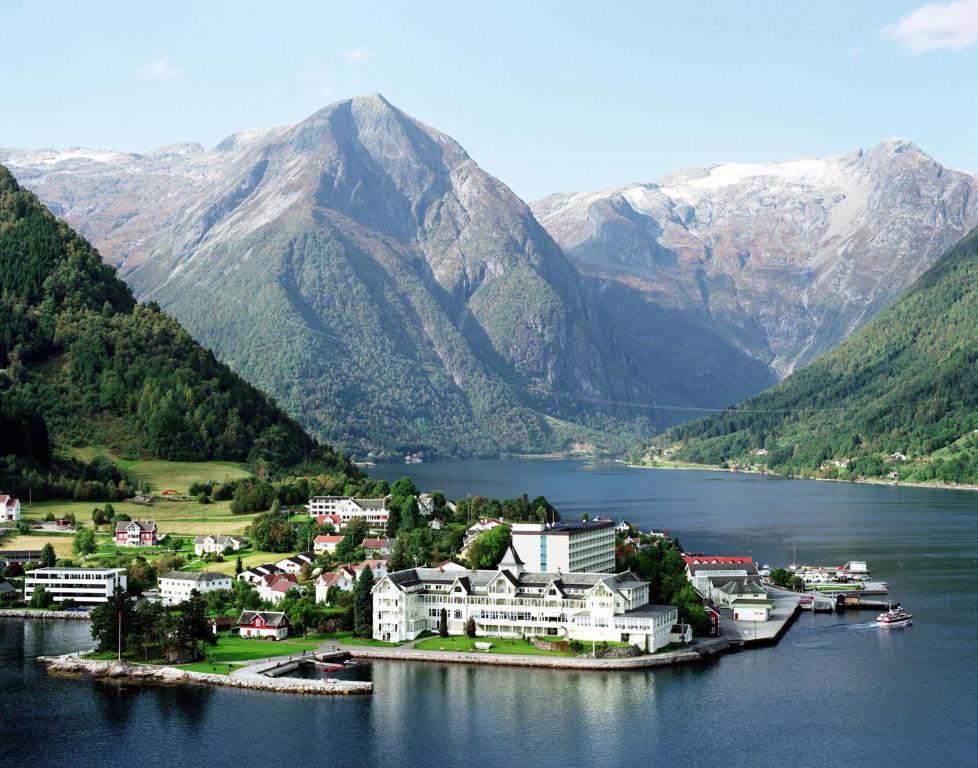 une ville d'une île dans une étendue d'eau avec des montagnes dans l'établissement Kviknes Hotel, à Balestrand