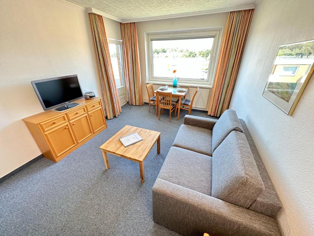 ein Wohnzimmer mit einem Sofa, einem TV und einem Tisch in der Unterkunft Appartement 156 in Westerland