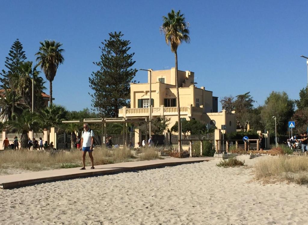 um homem andando na praia em frente a uma casa em Villino Vanzetti 1930 em Cagliari