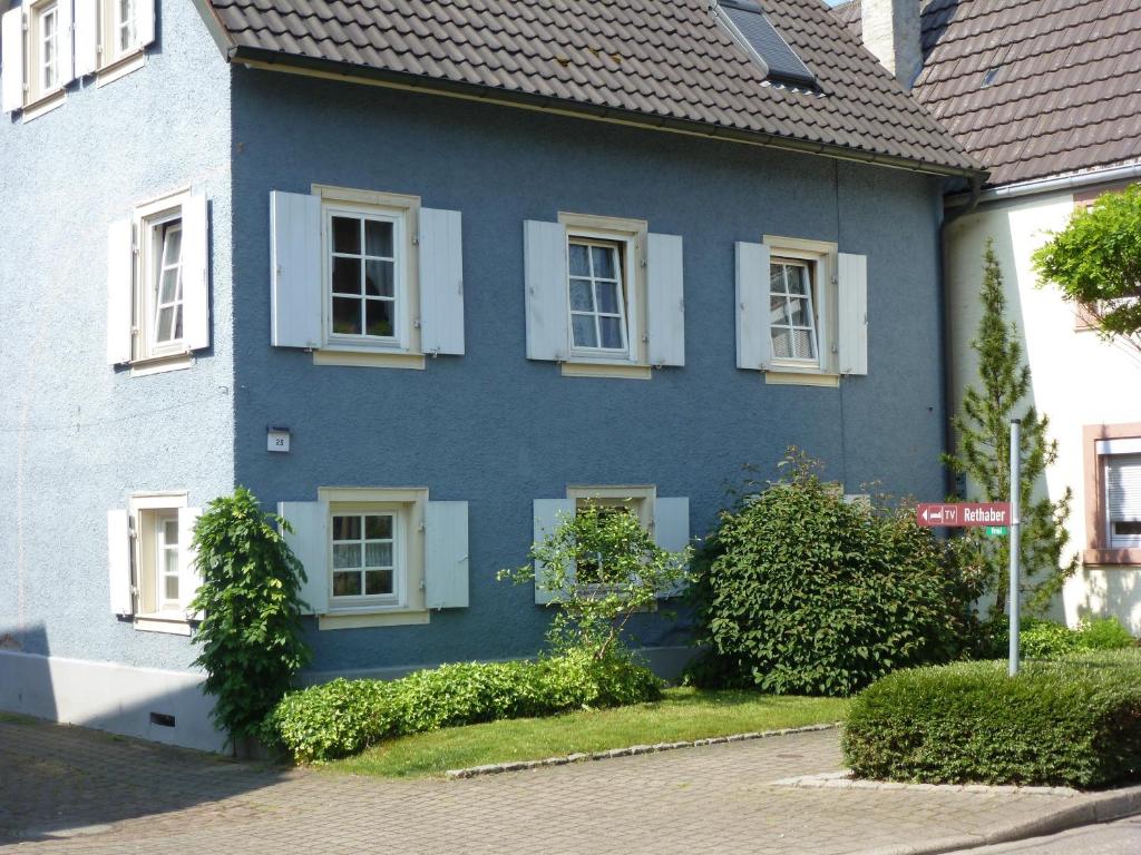 a blue house with white windows on a street at Privatzimmer Rethaber in Ringsheim