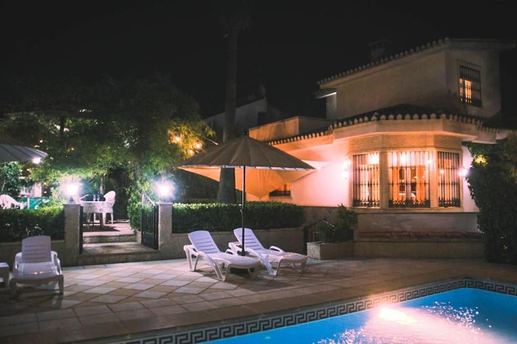 - deux chaises et un parasol à côté de la piscine dans l'établissement Villa del Mamut, Padul Granada, à Padul