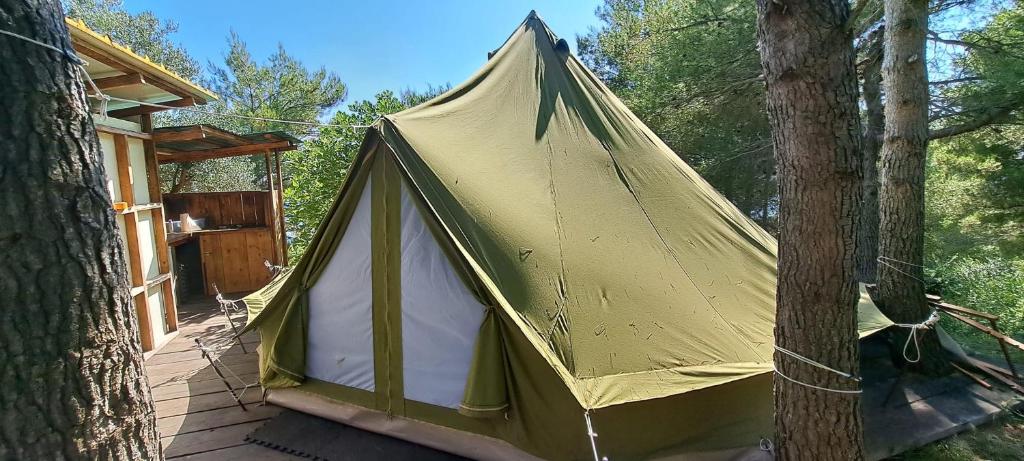 a yellow tent sitting on a deck next to trees at LJUBAC GLAMPING BELL TENT Robinson in Ljubač