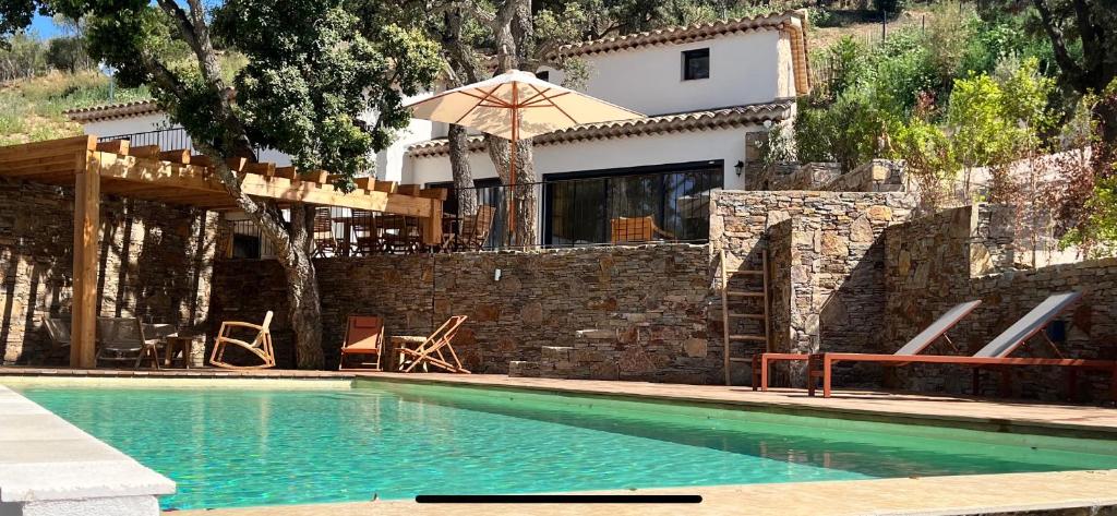une maison avec une piscine et un parasol dans l'établissement La Maison des Chênes - 5 étoiles, à Cavalaire-sur-Mer