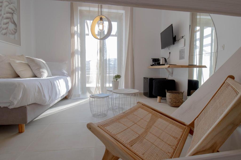 a white room with a bed and a chair in it at ALIRENE MYKONOS in Mykonos