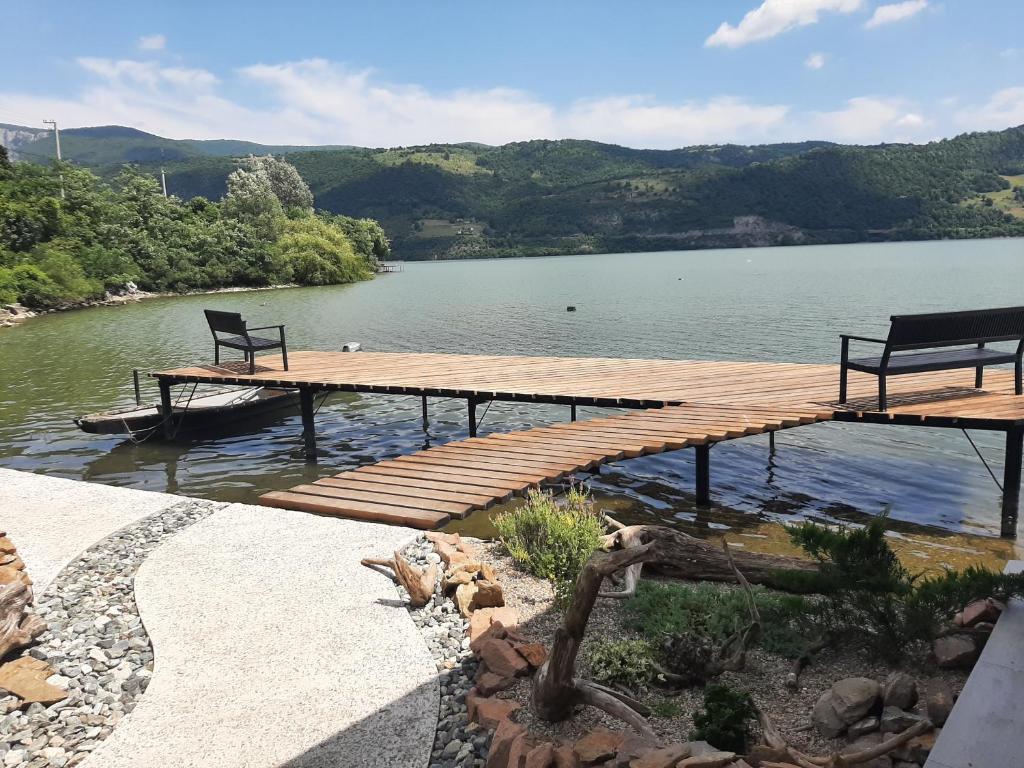 a wooden dock with two benches on top of a lake at La Piticu in Dubova