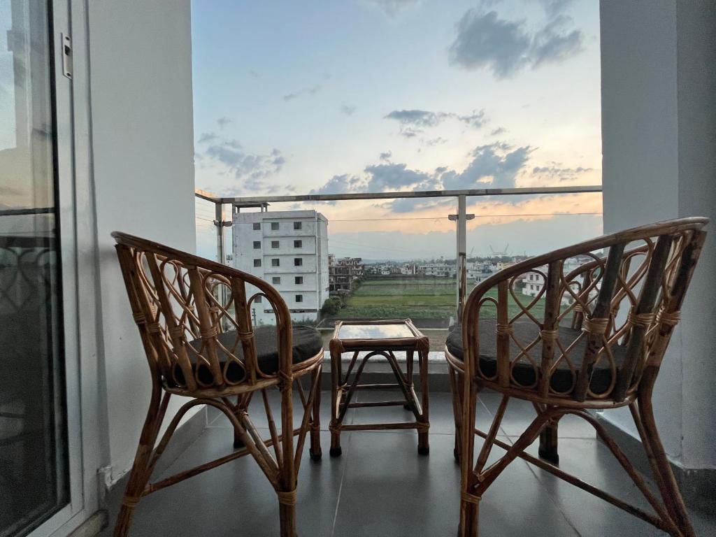 two chairs and a table on a balcony with a view at Ananta - Rishikesh Luxurious 2BHK in Rishīkesh