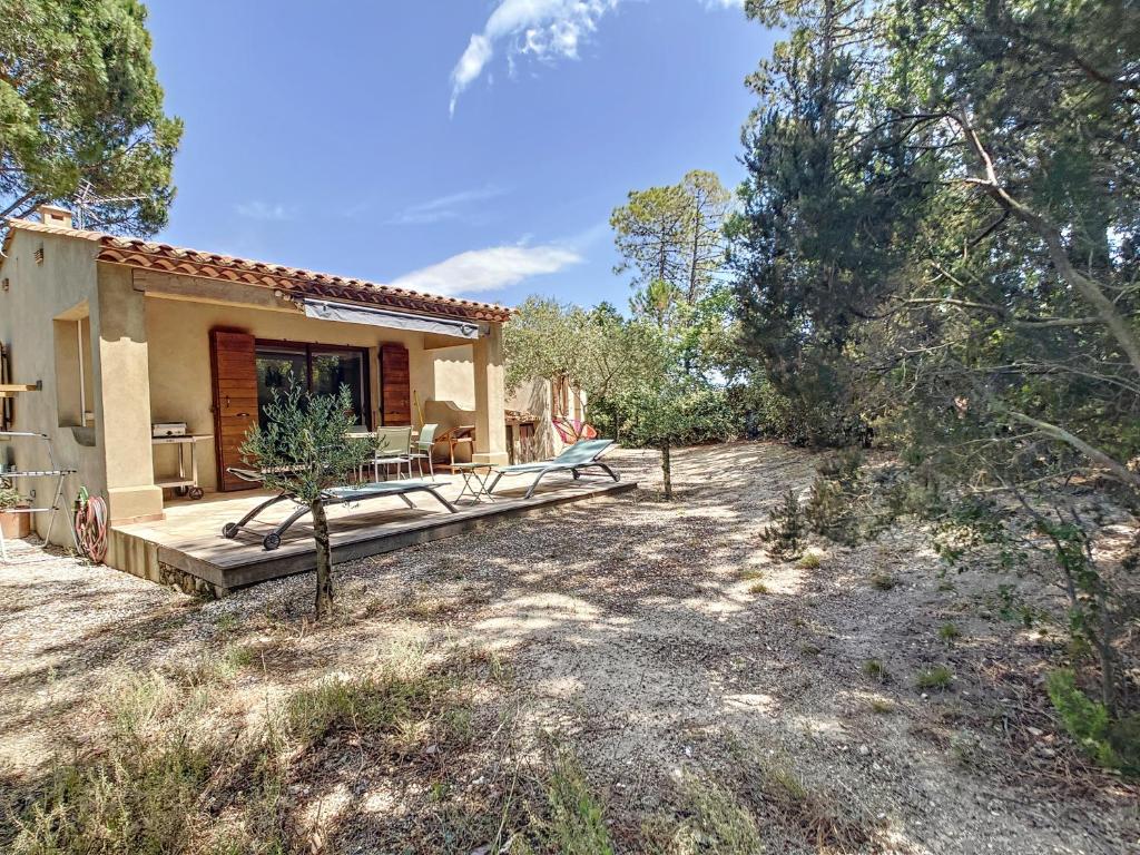 a house with a deck in the middle of a yard at La Petite Bergerie in Le Plan-de-la-Tour