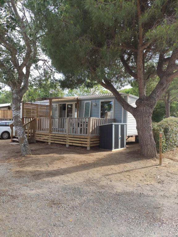 un camping-car garé sous un arbre dans une cour dans l'établissement Mobilhome climatisé et ombragé, à Port-la-Nouvelle