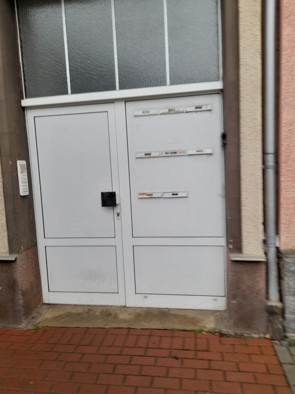 ein Paar weiße Garagentüren auf einem Gebäude in der Unterkunft Kleine Wohnung für Monteure und Dienstreisen in Zwickau