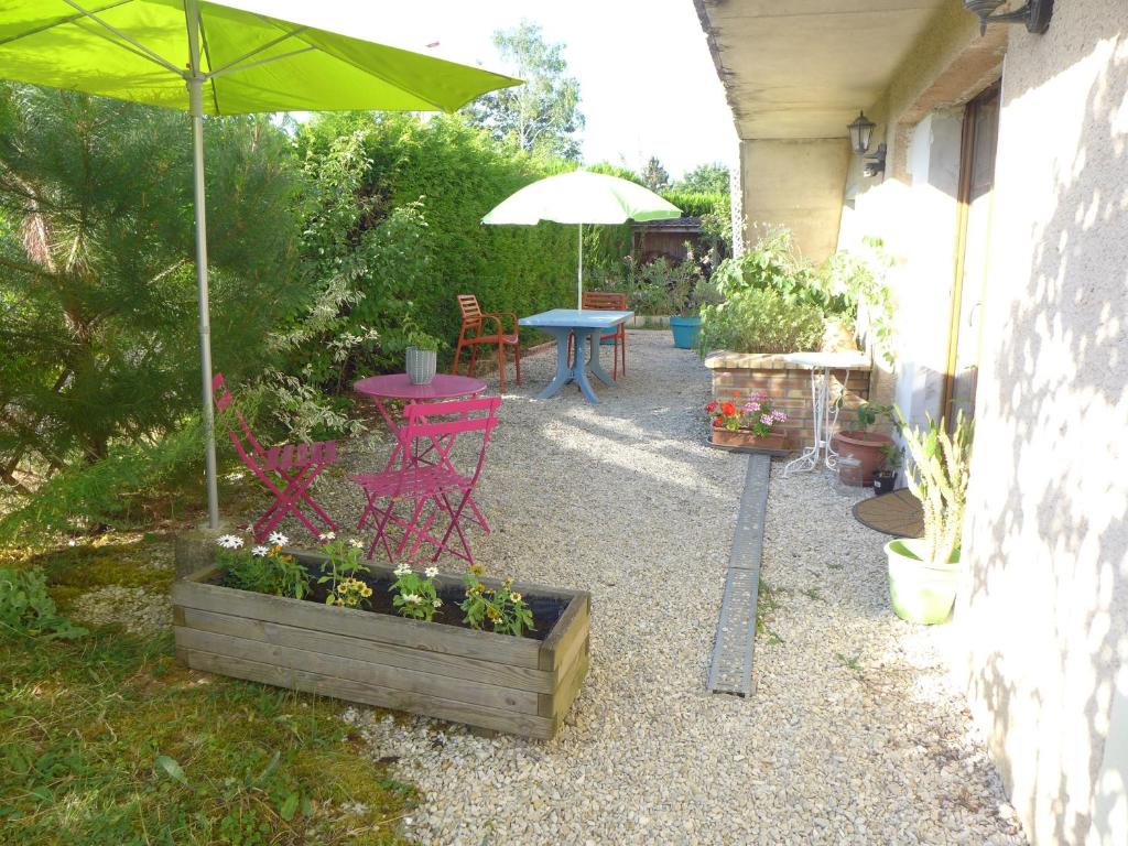 eine Terrasse mit einem Tisch, Stühlen und einem Sonnenschirm in der Unterkunft Grand appartement au calme in Lérouville