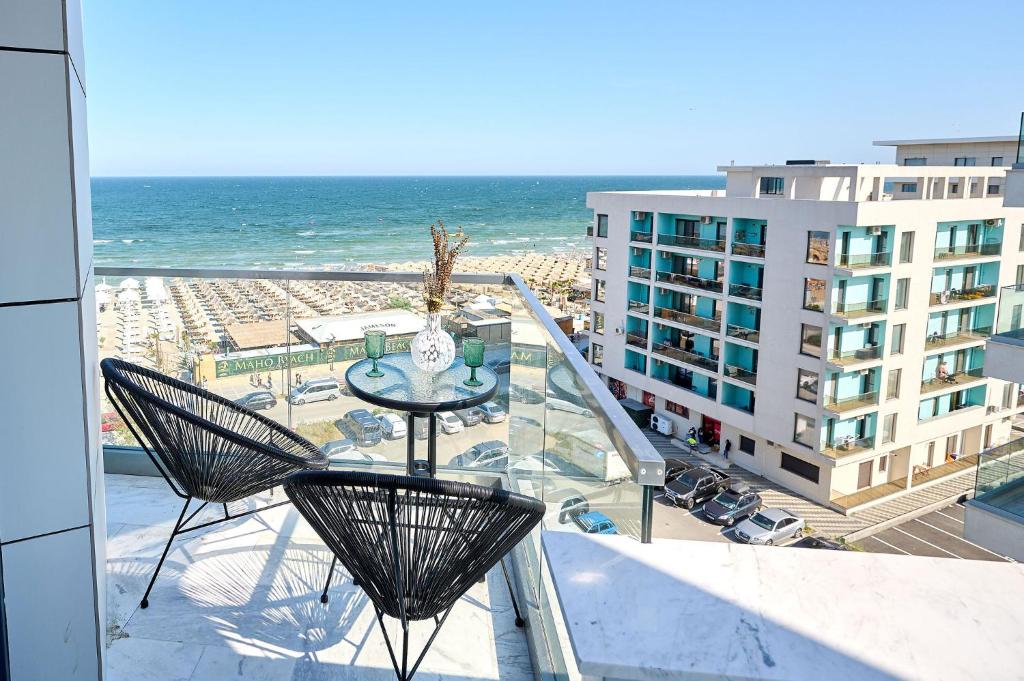 balcón con mesa, sillas y vistas al océano en Smarald Sea View Apartment in Infinity Beach Resort - parking, en Mamaia