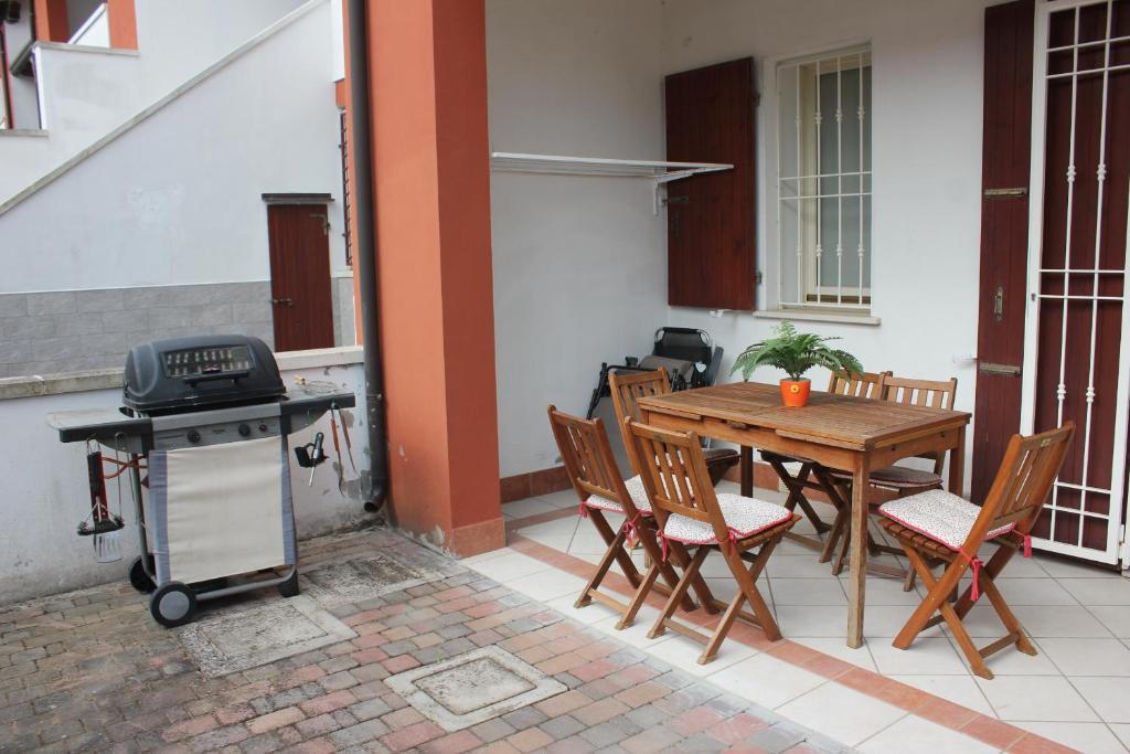 un patio con mesa, sillas y parrilla en Casa Pomposa, en Lido di Pomposa