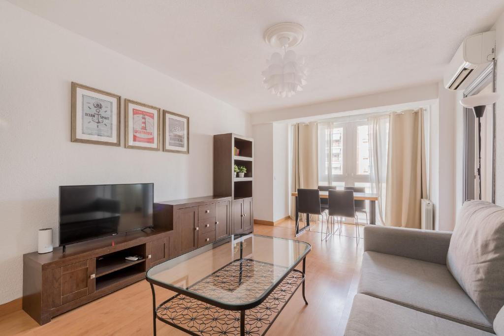 een woonkamer met een bank en een televisie bij Living Caja Mágica in Madrid