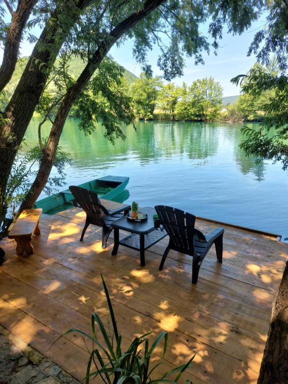 a patio with two chairs and a table next to a lake at FortUNA Holiday Home in Bihać