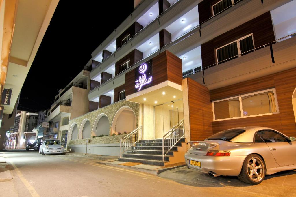 een auto die 's nachts voor een gebouw geparkeerd staat bij Achilleos City Hotel in Larnaka