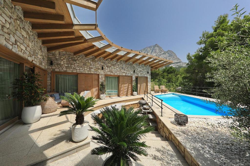 un patio con piscina y una casa en Villa BIOKOVO BAST, en Bast