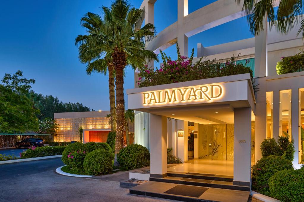 Palmyard Hotel في المنامة: فندق فيه نخلة امام مبنى