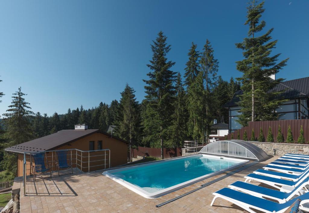 a swimming pool with two lounge chairs and a house at Апарт- готель SunRay Skhidnytsya in Skhidnitsa