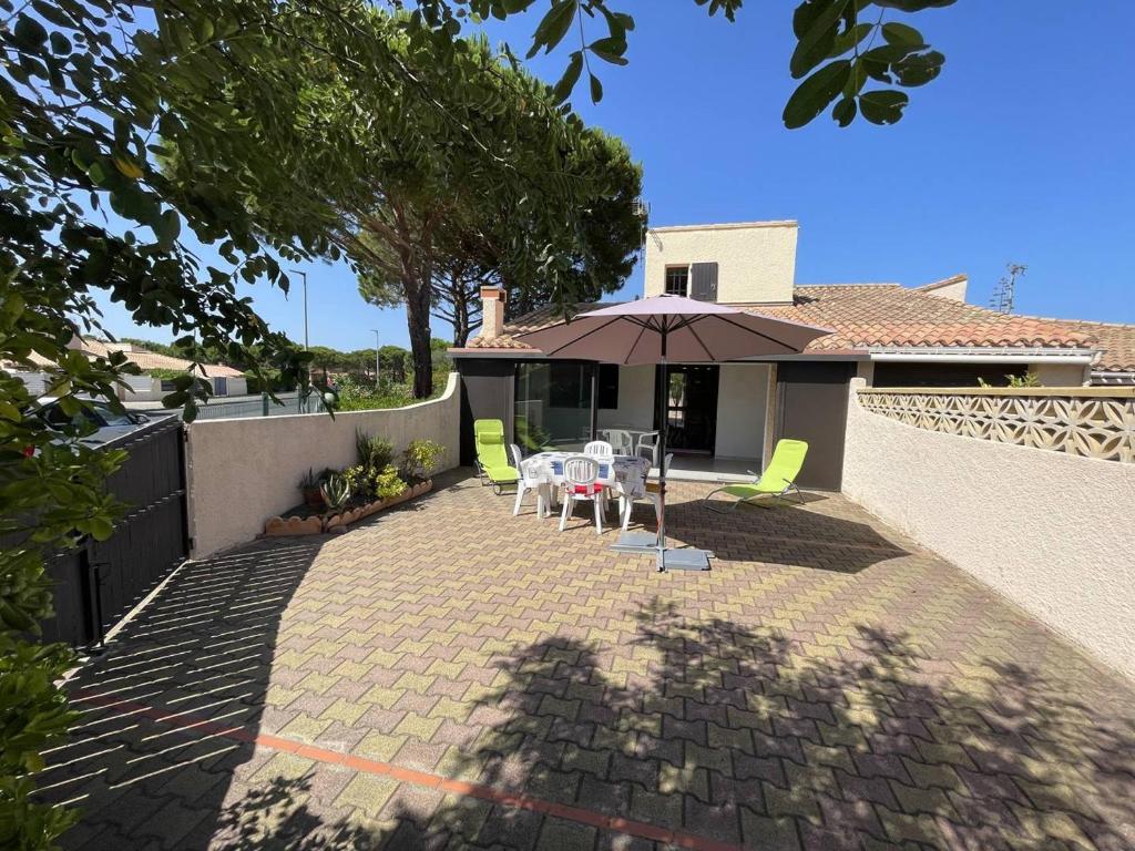 un patio avec une table, des chaises et un parasol dans l'établissement Jolie Villa 3 Pièces avec Véranda, Terrasse, Parking Sécurisé et Animaux Admis à Saint-Cyprien - FR-1-106-68, à Saint-Cyprien