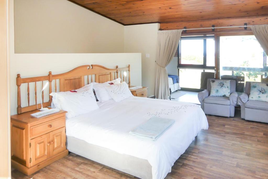 a bedroom with a large white bed and two chairs at Shalom Self Catering in Kleinmond
