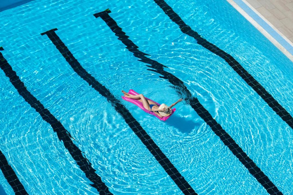 a woman laying on a raft in a swimming pool at Grand Hotel & Riviera in Lido di Camaiore