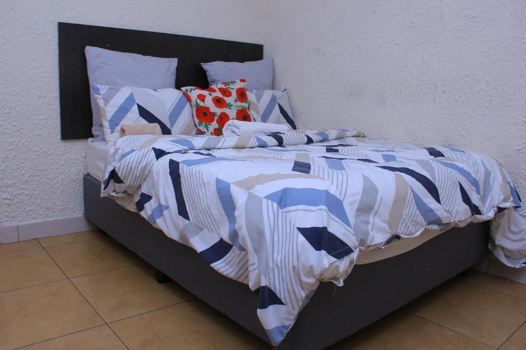 a bed with a blue and white comforter and pillows at MILLY GUEST HOUSE in Johannesburg