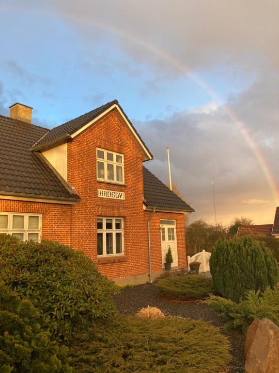 einen Regenbogen am Himmel über einem Backsteinhaus in der Unterkunft Large modern family room - “Arnely” in Tommerup