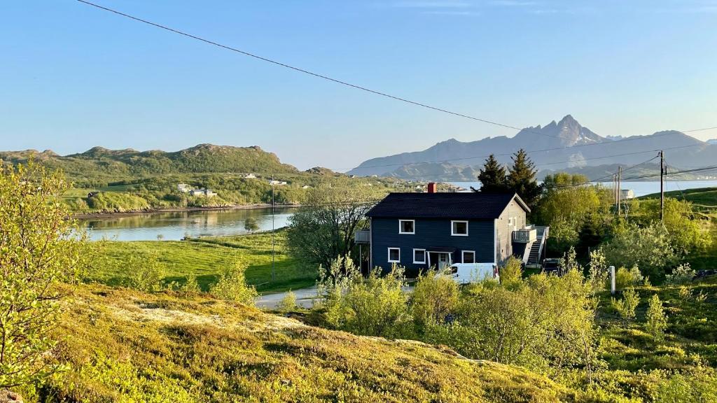 une maison bleue sur une colline à côté d'une rivière dans l'établissement EG Apartment, à Leknes