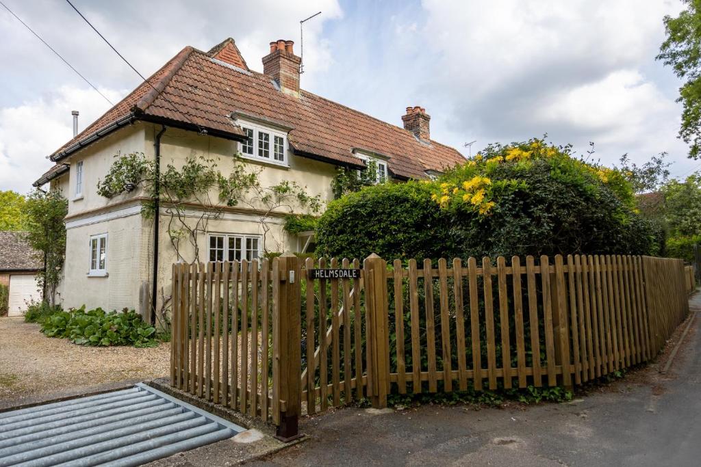 a wooden fence in front of a house at Spacious family cottage with private garden and forest walks in Burley